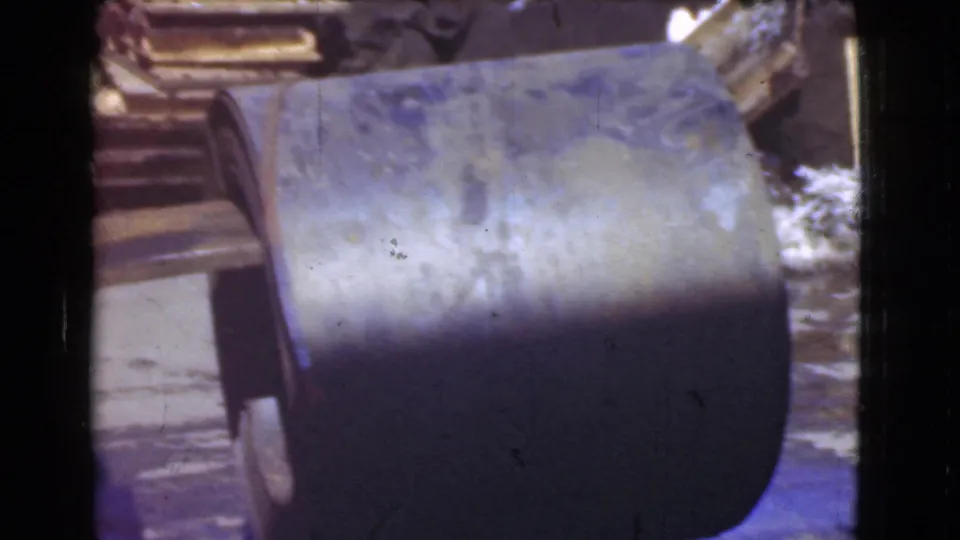 A close view shows a curved metal scoop or bucket attached to machinery in the industrial setting.