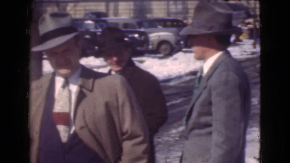Several adult men in hats and formal coats stand together on a snowy Cleveland street in this 1939 home-movie frame.