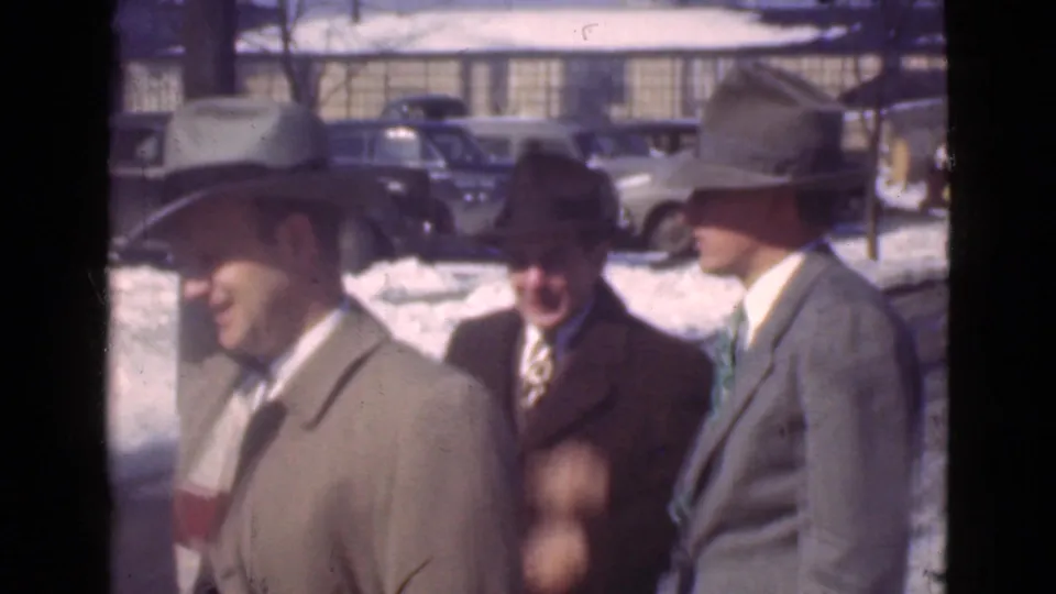 Three men in suits, hats, and overcoats stand near a snowy Cleveland roadside with prewar cars visible behind them.