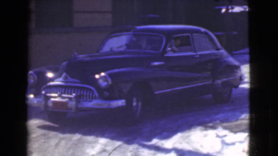 The parked sedan is shown from the front quarter on a snow-covered Cleveland street, with grille, bumper, and headlamps visible.