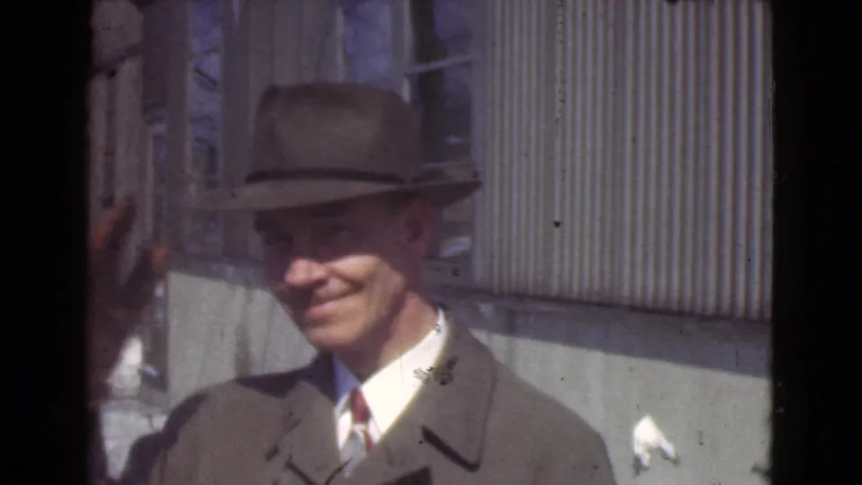 In the Cleveland 1939 home movie, the suited man smiles as the hat casts shade across his face near the wall.