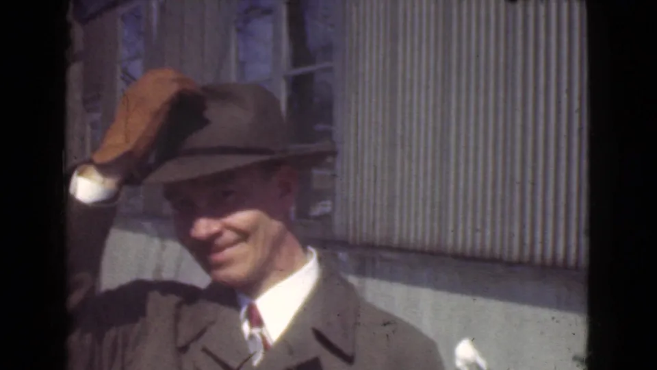 The 1939 Cleveland clip shows the man lifting or tipping his fedora in a friendly gesture toward the camera.