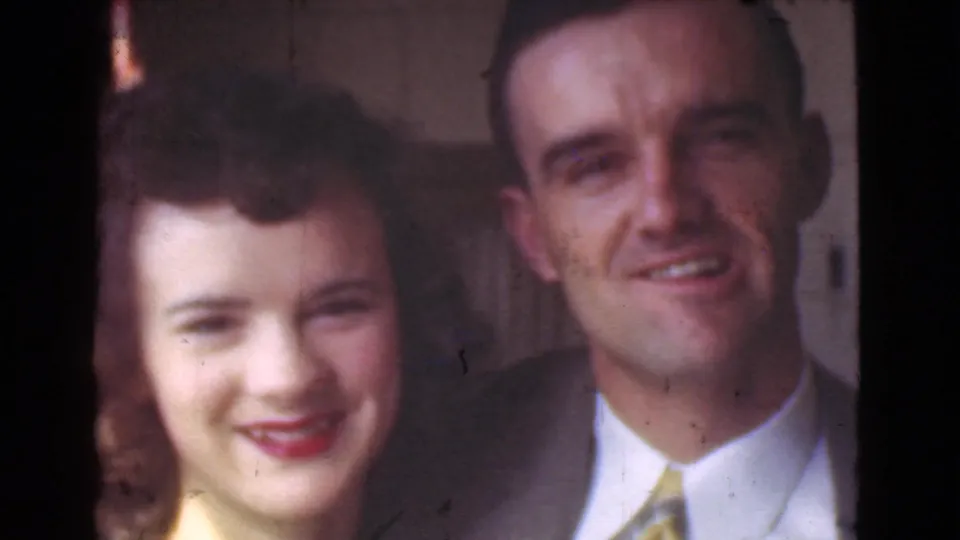 The couple remains in close view in the Cleveland street scene, with the man in a suit and the woman wearing a light dress and lipstick.