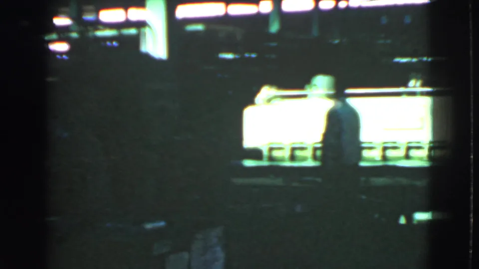 A silhouetted figure appears beside a bright machine or conveyor in the dim 1939 Cleveland industrial scene.
