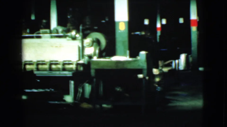 Factory-floor view in Cleveland, 1939, with machinery, marked support columns, and an indistinct worker figure in low light.