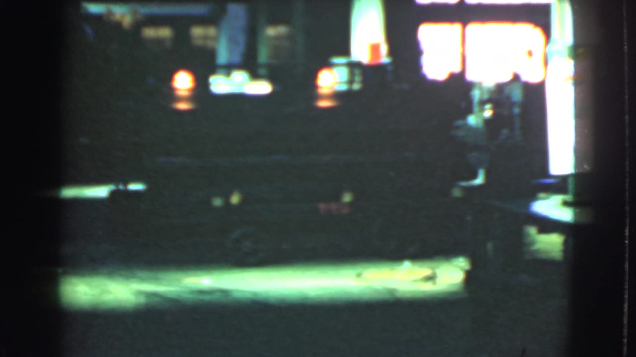Night street scene with bright station entrance and indistinct vehicle lights.