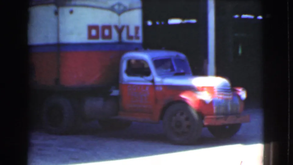 1939 Cleveland frame showing a red cab and white Doyle Freight Lines truck body near a lit street or station frontage.