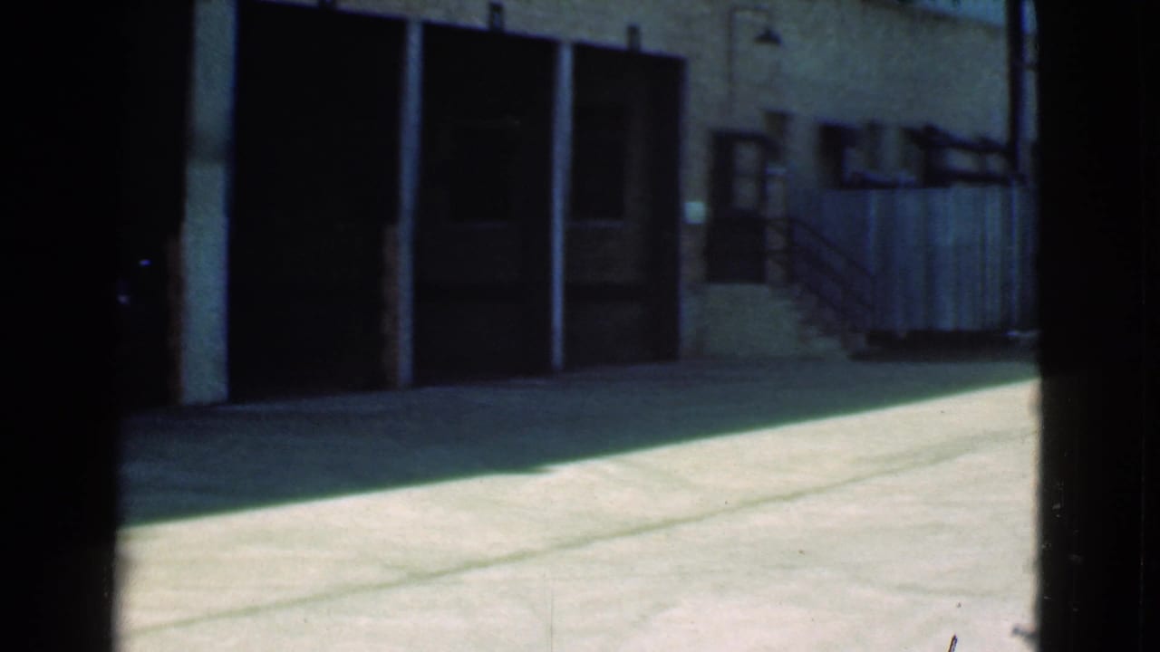 Garage doors, brick wall, pavement, and a wooden fence near stairs.