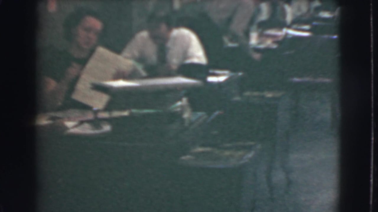 Men and women at desks reading and handling papers.