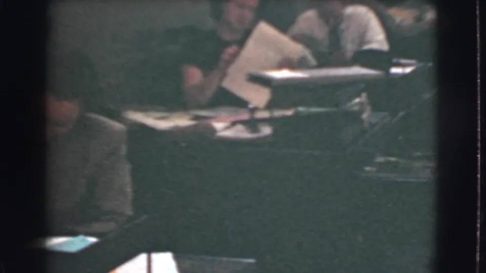 Dim 1939 office interior with workers seated among papers, folders, and desk lamps in Cleveland.