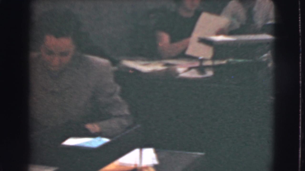 1939 Cleveland office scene showing a seated man near a desk while workers behind him handle papers at nearby workstations.