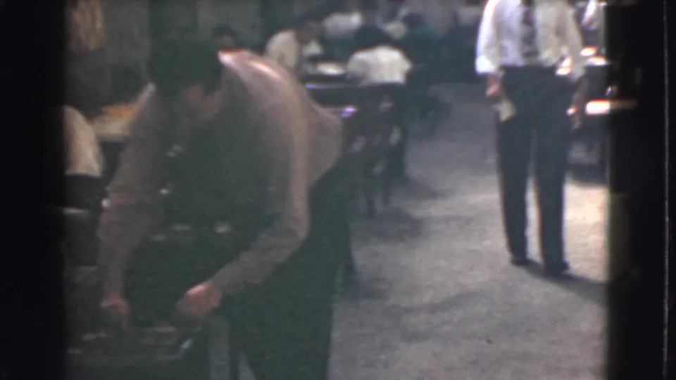 1939 Cleveland office view with a man bending near a workstation and another man standing in the aisle between desks.