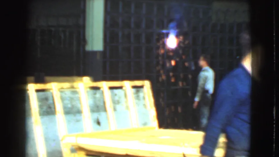 A later frame shows workers near stacked rectangular materials and a bright light source inside the same Cleveland industrial warehouse setting.