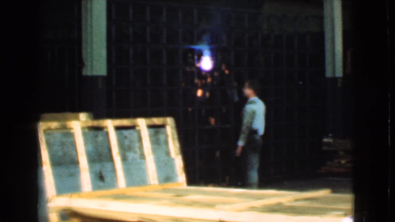 1939 Cleveland 8mm frame showing a worker watching welding at a metal gate in an industrial timber yard.