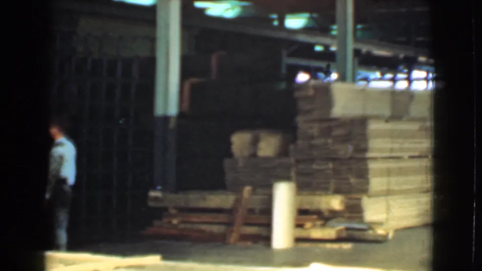 1939 Cleveland 8mm frame showing the worker partly exiting the view beside lumber stacks in an industrial yard.