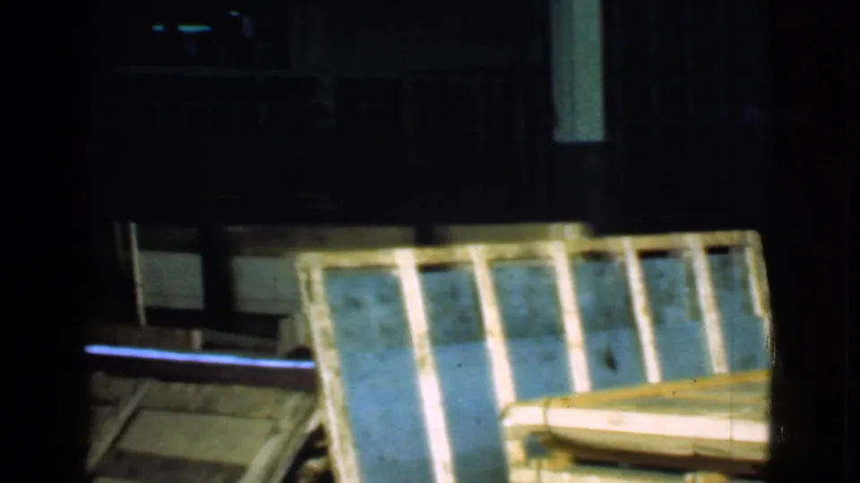 Wooden crate or pallet panels sit in a shadowed Cleveland warehouse interior, with dark structural elements behind them.