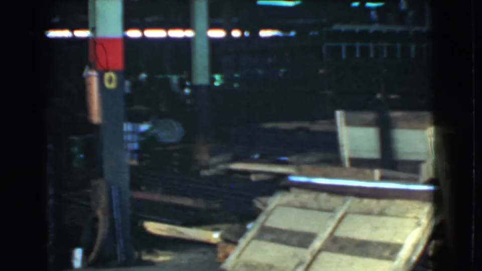 A dim warehouse view shows columns, scattered boards, and crate frames in the supplied Cleveland industrial footage.