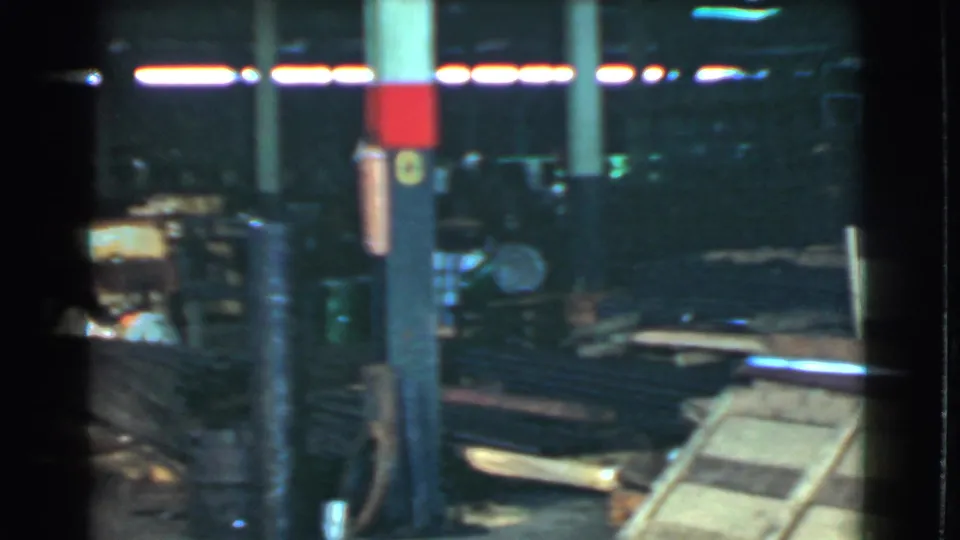1939 Cleveland home-movie frame showing a dark, cluttered yard or shed area with scattered materials and soft 8mm color.