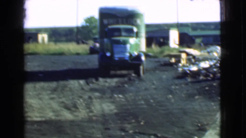1939 Cleveland footage shows a green truck moving or positioned in a dirt yard, with debris and trailer-like equipment along the side.
