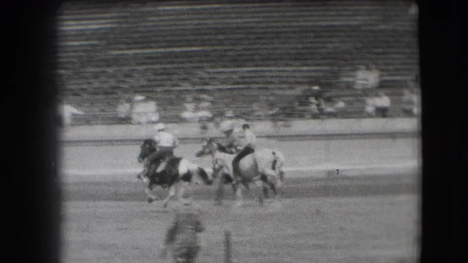 1941 Denver rodeo-practice footage shows several cowboys on horseback grouped in a dirt arena before mostly empty bleachers.