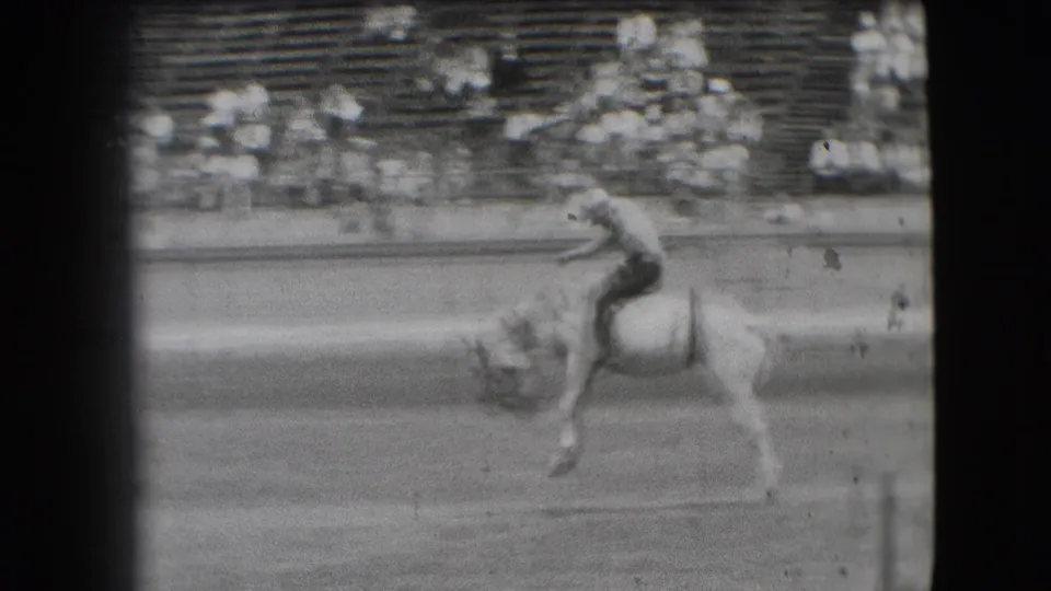 1941 Denver rodeo frame showing the rider still on the bucking horse as the action moves across the dirt arena.