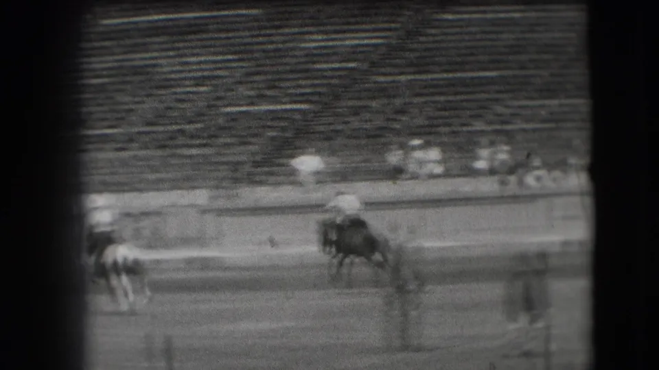 Distant 1941 Denver home-movie view of polo riders on horseback moving across an outdoor arena with sparse seating in the background.