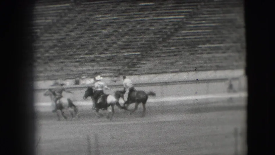 Polo players on horses converge near the arena rail during a 1941 Denver outdoor match, seen through soft 8mm home-movie focus.