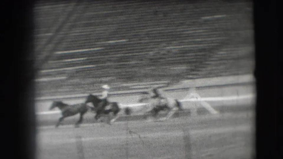 Fast-moving polo riders gallop across the Denver arena field, with motion blur and dark 8mm frame edges emphasizing the home-movie scan.