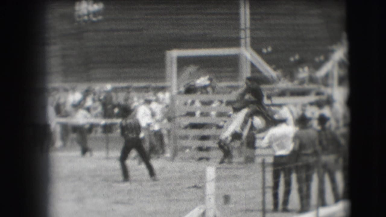 1941 Denver home-movie frame showing a horse and rider near an obstacle as spectators watch from the arena edge.