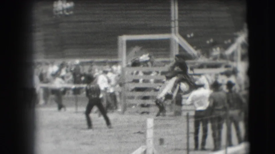 1941 Denver home-movie frame showing a horse and rider near an obstacle as spectators watch from the arena edge.