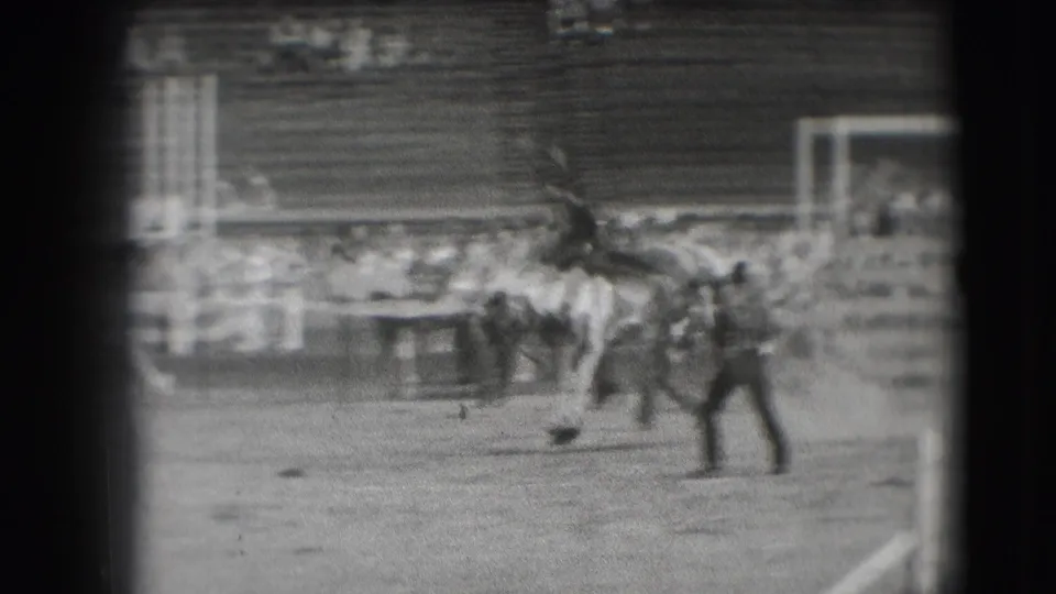 Horse and rider cross the arena in the supplied 1941 Denver clip, with a jump structure and bleachers in the background.