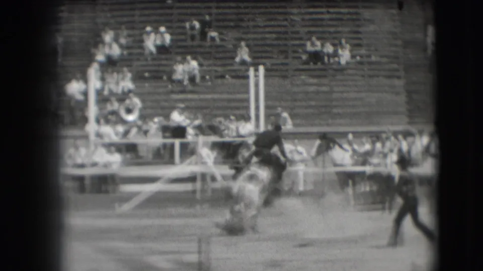 A horse and rider move through the obstacle area in Denver, with spectators and what appears to be a band section in the stands.