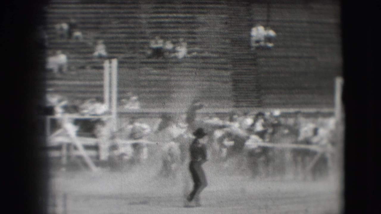 1941 Denver rodeo footage shows a cowboy on a bucking horse in a dusty arena with spectators seated in wooden bleachers.