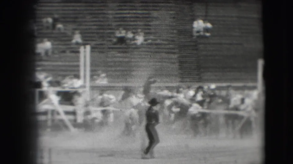 1941 Denver rodeo footage shows a cowboy on a bucking horse in a dusty arena with spectators seated in wooden bleachers.