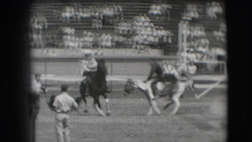 1941 Denver rodeo footage showing riders on bucking horses in an arena, with bleachers and a standing attendant visible nearby.