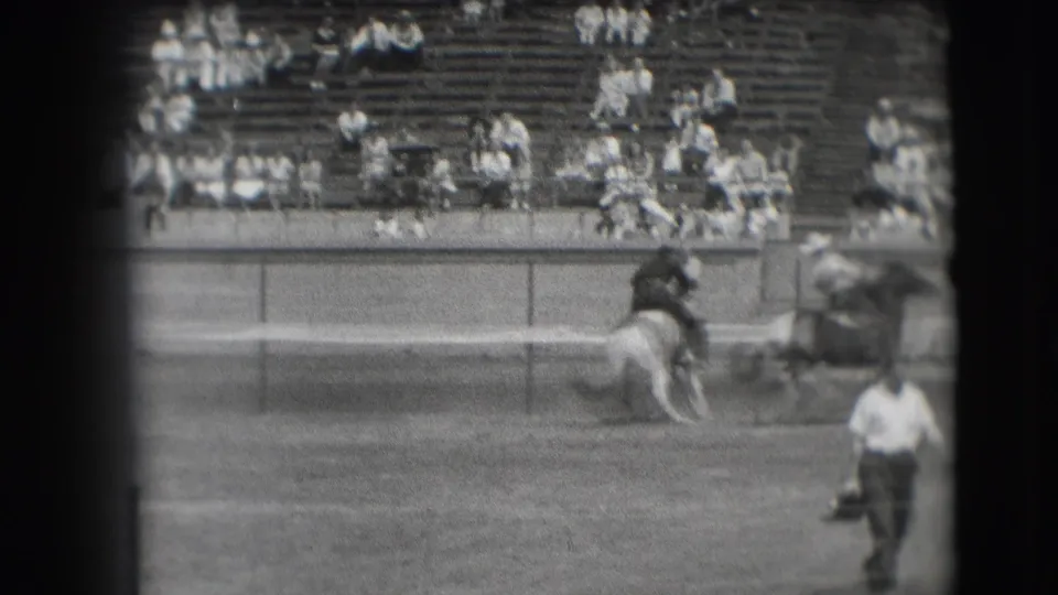 Rodeo arena view in Denver, 1941, with a mounted rider near the rail and a man walking across the open dirt area.