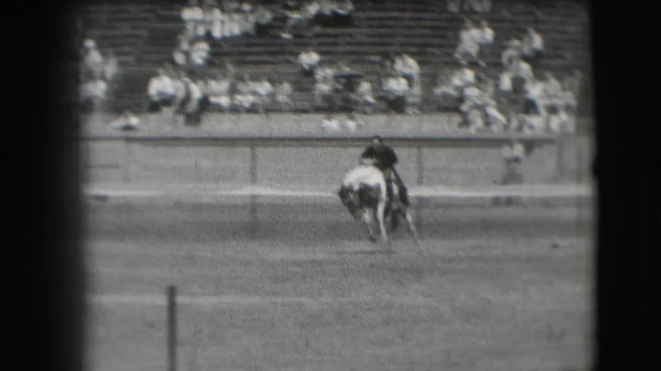 1941 Denver rodeo frame showing a horse bucking or twisting in the dirt arena, viewed from the spectator stands.