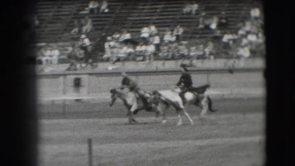 Denver rodeo home-movie frame from 1941 showing multiple horseback riders moving across the arena before a seated crowd.
