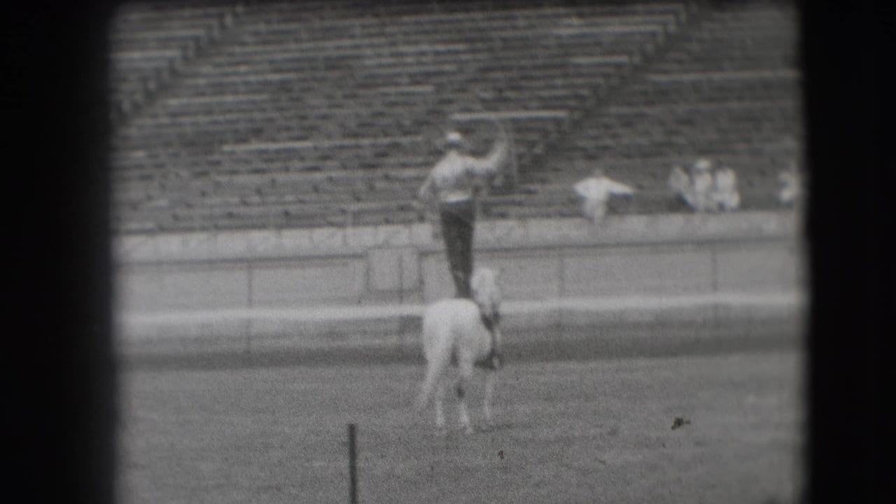 1941 Denver rodeo footage shows a man standing on a white horse with bleachers behind him.