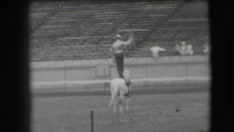 1941 Denver rodeo footage shows a man standing on a white horse with bleachers behind him.