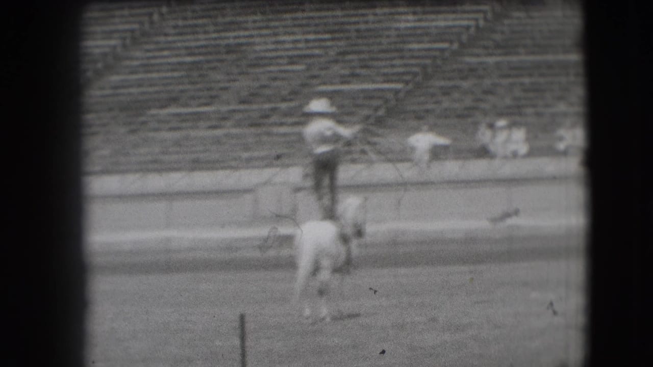In 1941 Denver rodeo footage, a cowboy in a light hat stands on a white horse before stadium bleachers.