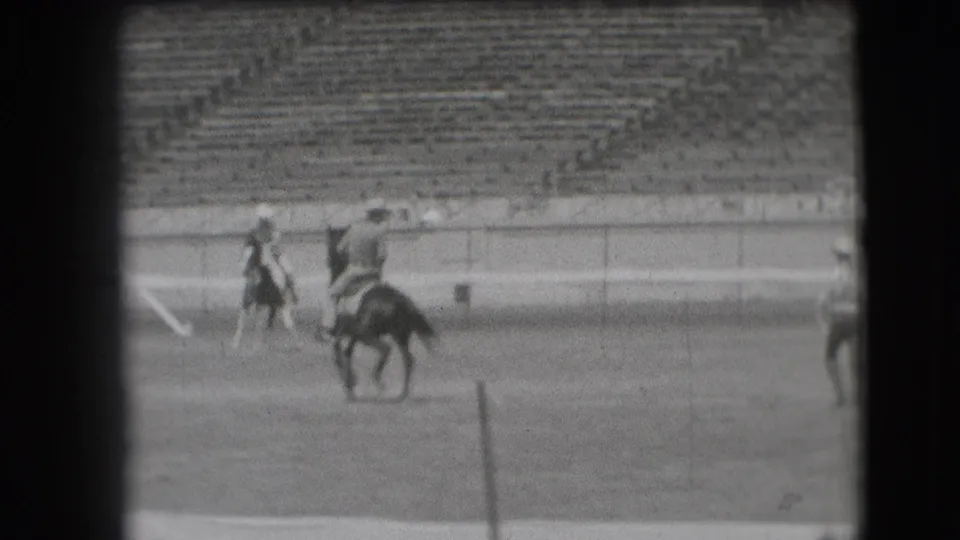 1941 Denver rodeo frame with mounted riders moving through the arena while spectators sit in the background stands.