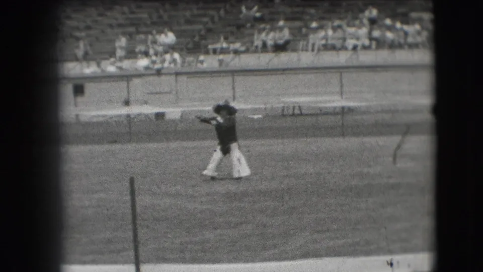 In 1941 Denver home-movie footage, a person in cowboy-style costume dances across a grassy stadium field before distant spectators.