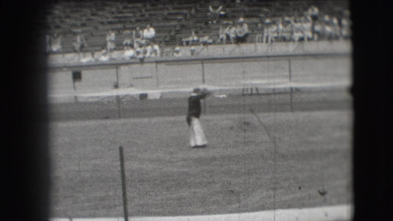 Denver 1941 home-movie frame showing a circus clown on grass in front of stadium bleachers.