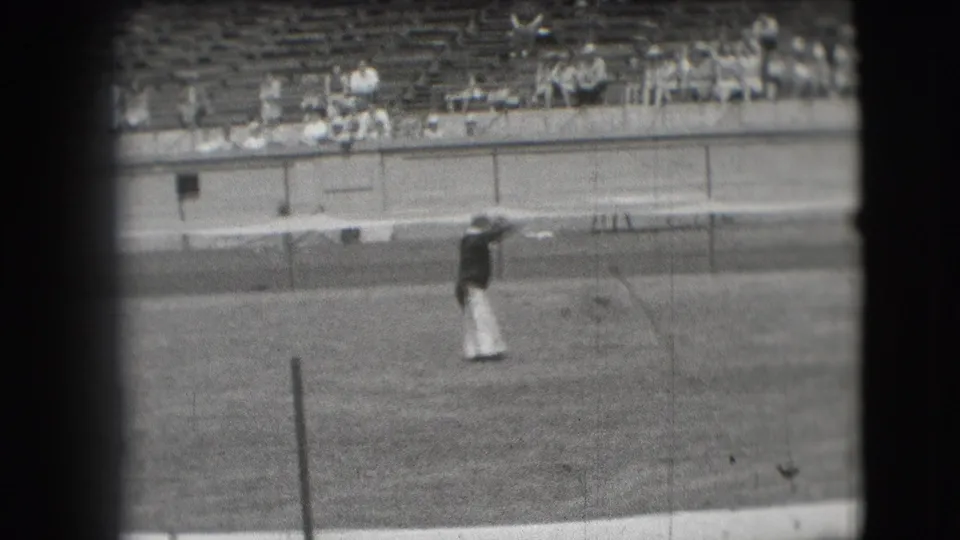 Denver 1941 home-movie frame showing a circus clown on grass in front of stadium bleachers.
