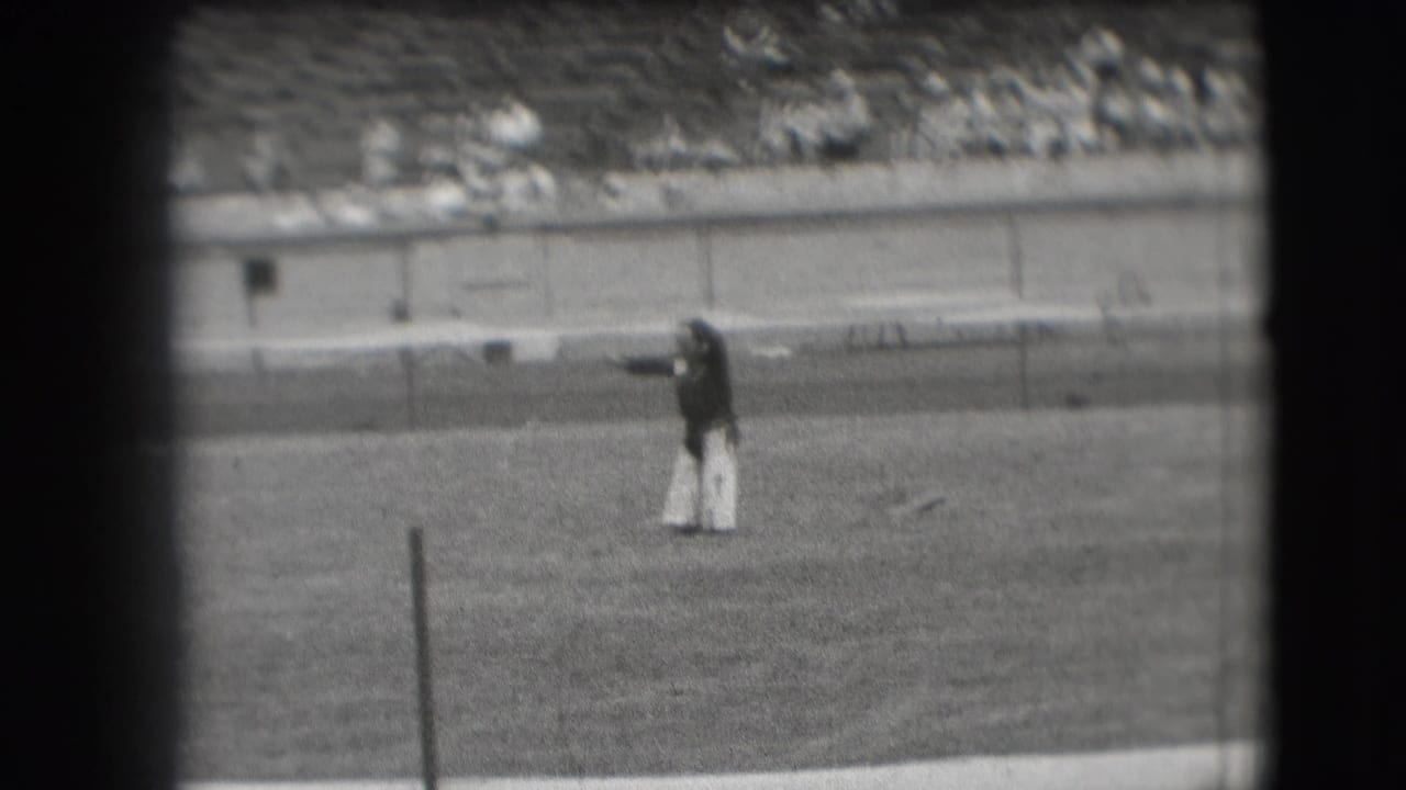 Denver 1941 frame of a clown extending an arm while performing on a stadium field.