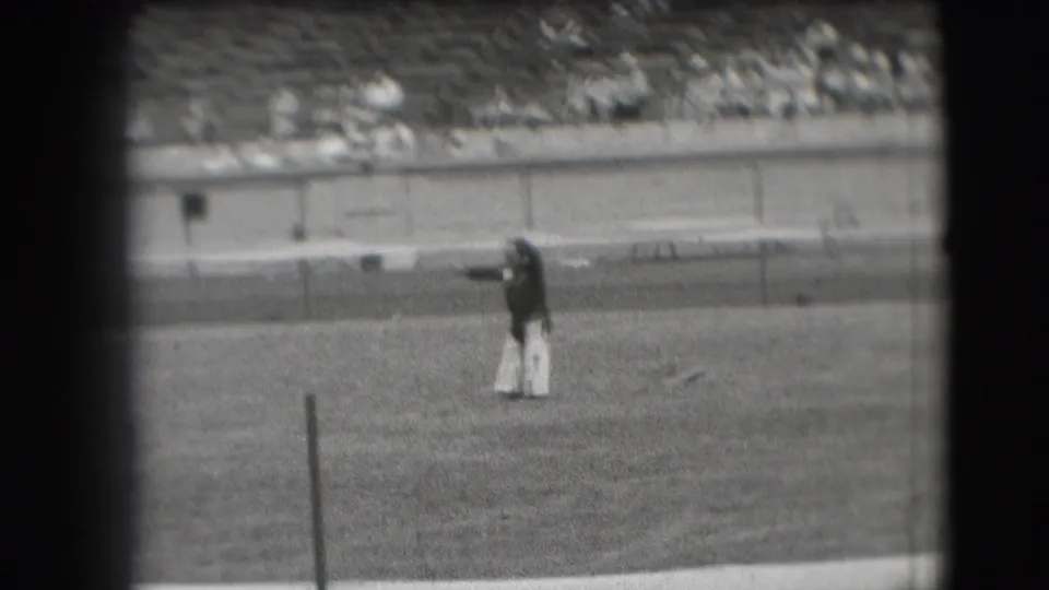 Denver 1941 frame of a clown extending an arm while performing on a stadium field.