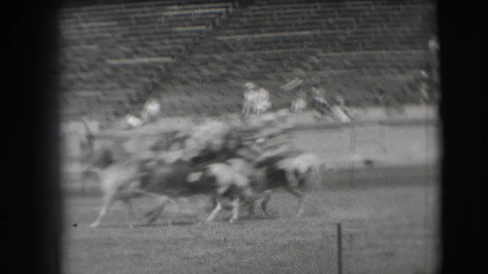 1941 Denver rodeo footage showing cowboys on horses moving across a stadium field, seen through grainy black-and-white 8mm framing.