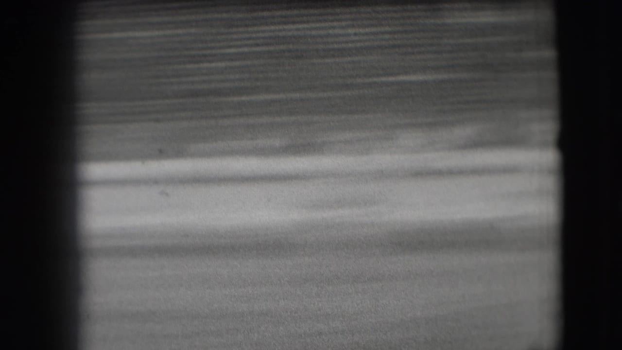 The final 8mm frame shows the stadium field and blurred seating after the rodeo riders have moved out of view.