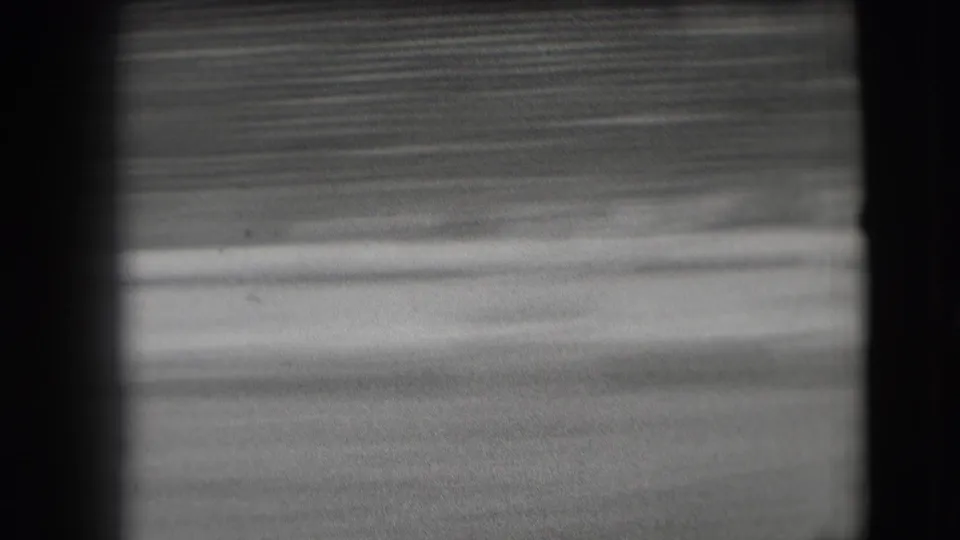 The final 8mm frame shows the stadium field and blurred seating after the rodeo riders have moved out of view.